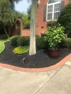 Black Rubber Mulch Landscaping Around Brick House
